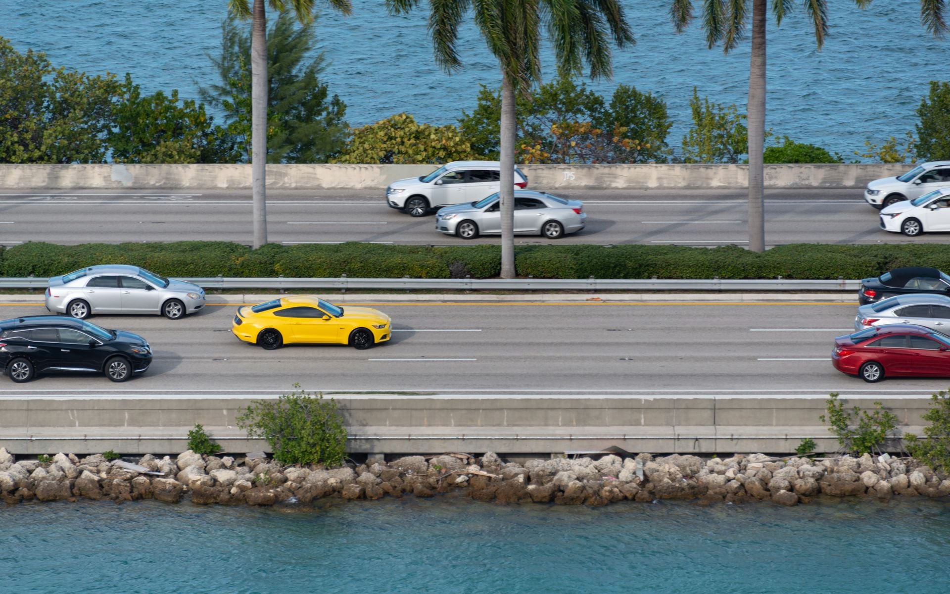 A coastal highway curving past palm trees and blue water on a Florida road trip