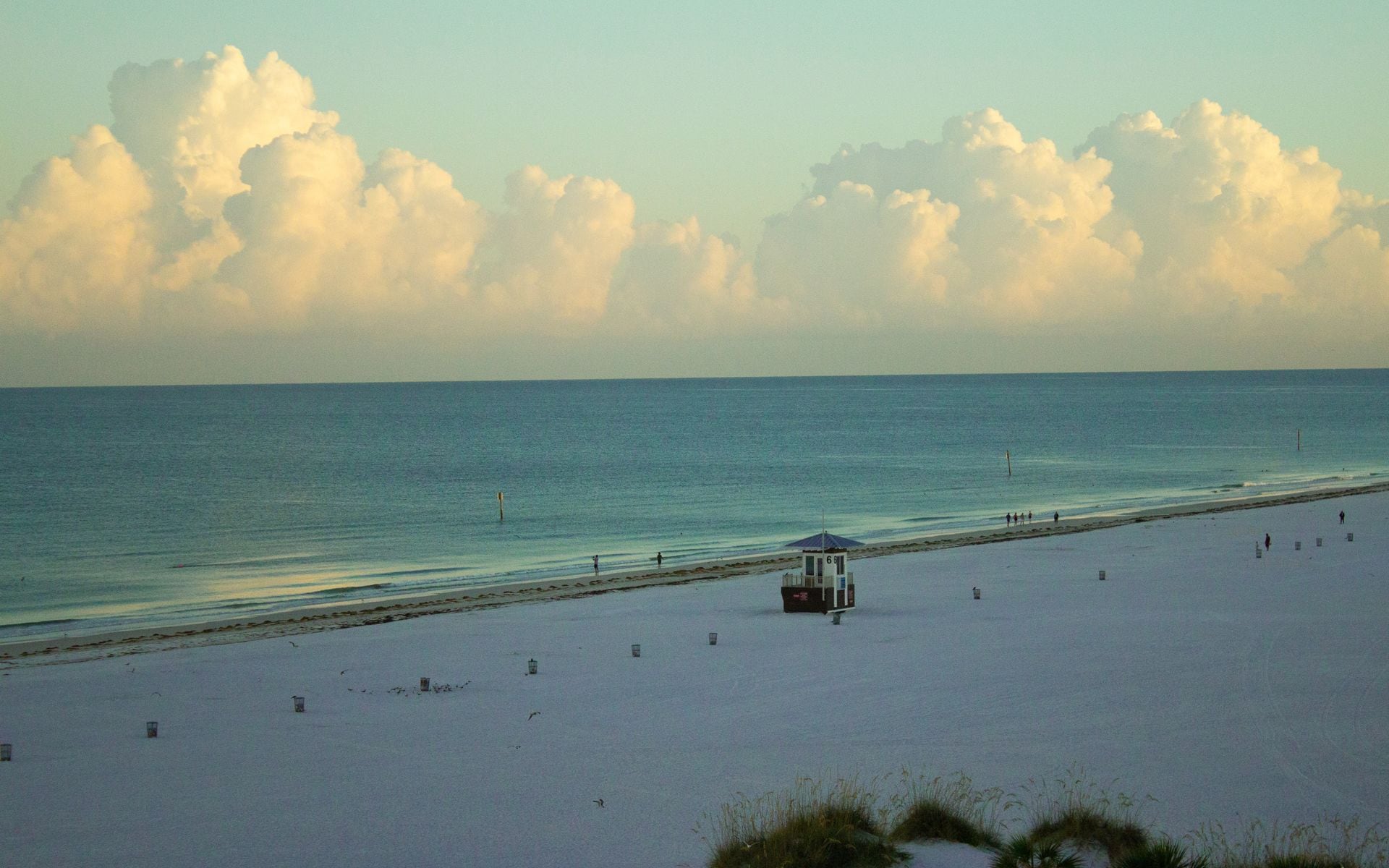 Empty white-sand Florida beach with calm turquoise water under a clear morning sky