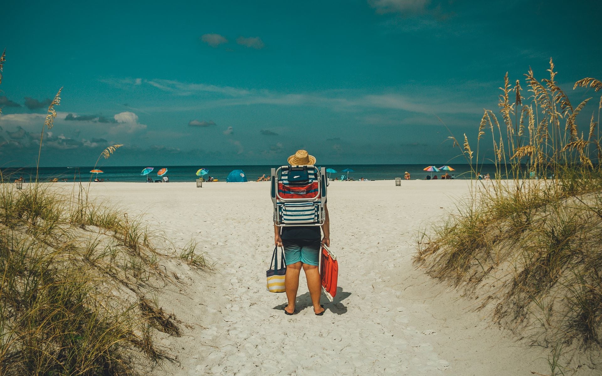 A family walking along a calm Gulf Coast beach in Florida with kids carrying pails