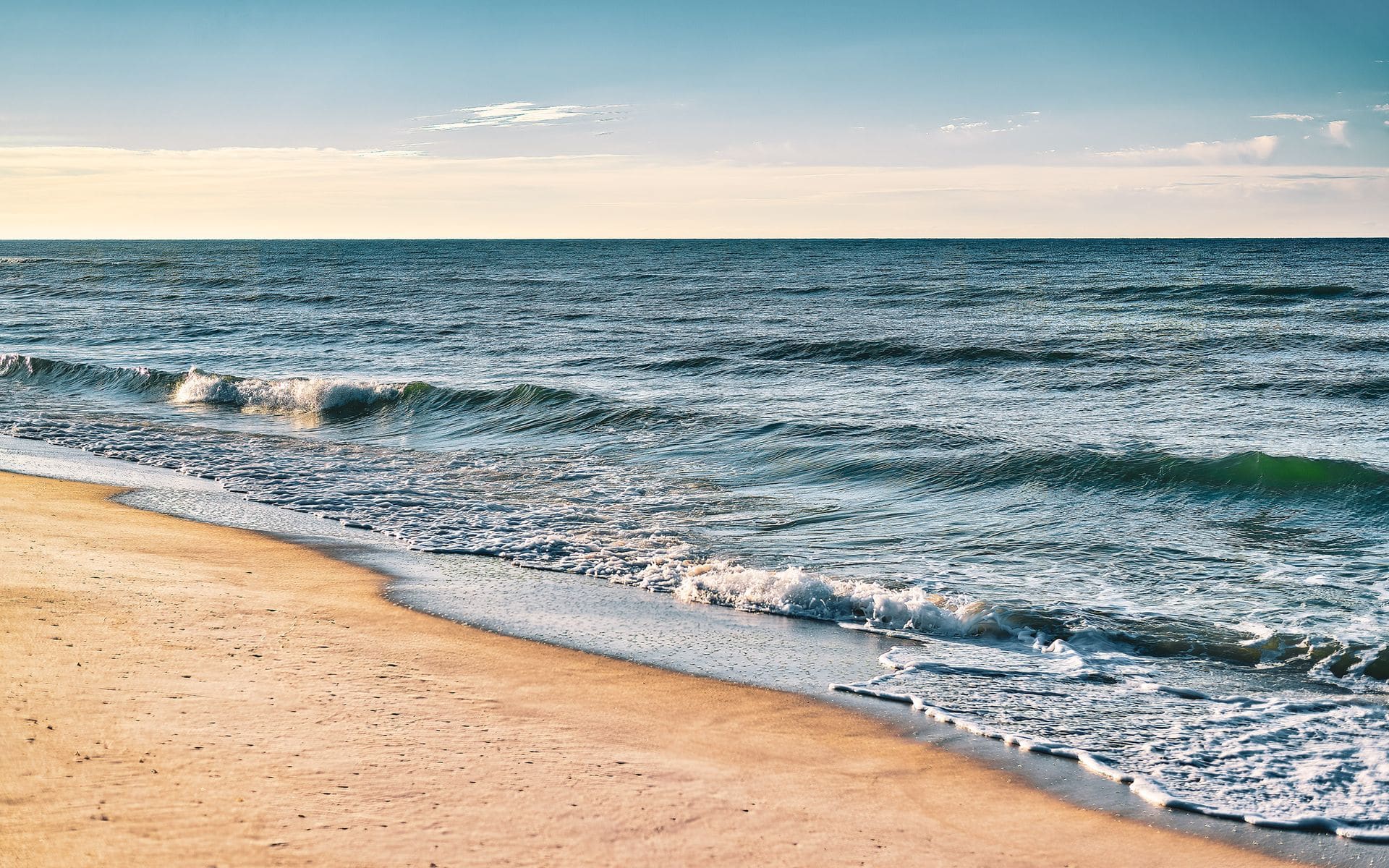 Split view of calm Gulf water and Atlantic surf on a Florida beach day
